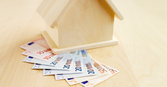 Mutuo rappresentato da una casa in miniatura e banconote