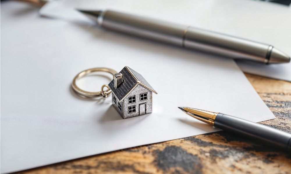 Portachiave di una casa e penna, simboleggiando le Case all’asta a Napoli.