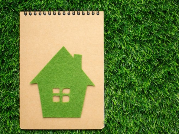 Quaderno con immagine di casa green, simboli di classe energetica dell'immobile elevata e dell'importanza della certificazione APE.