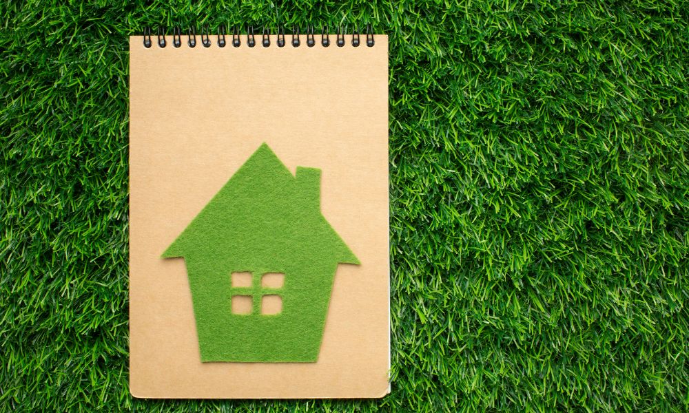 Quaderno con immagine di casa green, simboli di classe energetica dell'immobile elevata e dell'importanza della certificazione APE.