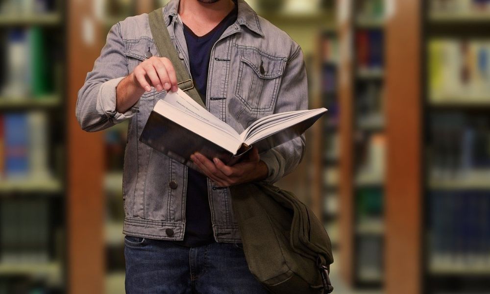 Studente fuorisede che sfoglia un libro, che sfrutta l'agevolazione di detrazione affitto per studenti.