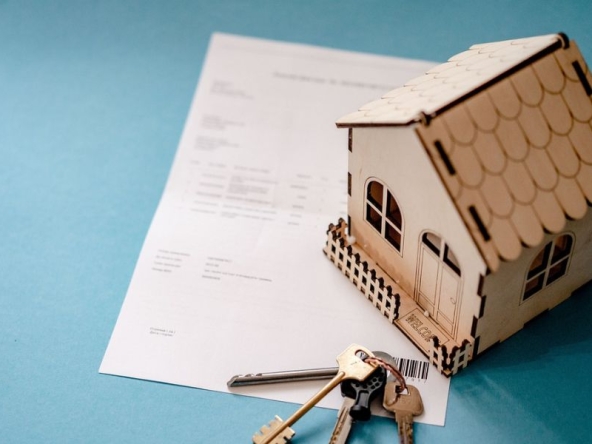 Casa in miniatura con chiavi e documenti, rappresentazione dei documenti compravendita necessari per vendere casa.